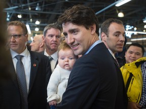 Prime Minister Justin Trudeau holds a baby as he  visits the Seaport Farmers' Market in Halifax on Saturday, April 2, 2016. THE CANADIAN PRESS/Andrew Vaughan