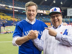 Montreal Mayor Denis Coderre, right, shares a laugh with Toronto counterpart John Tory prior to the Blue Jays facing the Boston Red Sox in a spring training baseball game Saturday, April 2, 2016 in Montreal. THE CANADIAN PRESS/Paul Chiasson