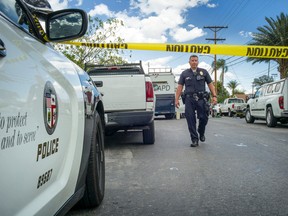 In this Tuesday, March 29, 2016 photo, police work the scene where a man was found shot to death and a woman fatally stabbed, in Los Angeles. A Los Angeles man charged with fatally shooting his 29-year-old son for being gay had repeatedly threatened to kill him over his sexual orientation, prosecutors say. Amir Issa was found shot to death just outside the family home on Tuesday. While the Los Angeles County district attorney's office charged father Shehada Issa, on Friday with murder as a hate crime in the son's death, investigators on Saturday still were trying to determine responsibility for a second killing at the home discovered by police at the same time, that of Amir's mother, police spokesman Officer Mike Lopez said. (David Crane/Los Angeles Daily News via AP)