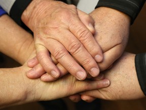 A man who found housing thanks to local social-service agencies clasps hands with some of those who helped him at the Canadian Mental Health Association office in Belleville Wednesday, March 30, 2016. He said he became homeless despite a lack of addiction and “frittered away” his assets. He’s now rebuilding his life at age 73.