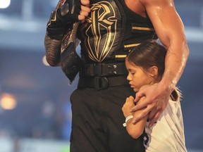 Roman Reigns celebrates with his daughter at his side after winning the World Wrestling Entertainment World Heavyweight championship at WrestleMania 32 in Arlington, Texas, on Sunday night. (Ricky Havlik/For Postmedia Network)