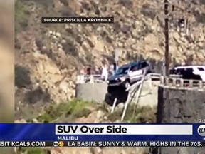 An SUV is seen dangling off the side of a cliff on Malibu Canyon Rd. east of Los Angeles. (CBS Los Angeles YouTube screenshot)