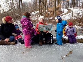 Caren Thayer, program facilitator at Wild Child Outdoor Playgroup, enjoys reading to the families who drop-in on this weekly event. (Photo submitted)