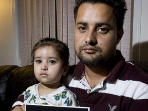 Manjinder Litt holds his daughter Kiranjot, 2, and a photo of his wife, Poonam. His sister is accused of stabbing Poonam to death in 2009. His father and brother-in-law are accused of being accessories after the fact.