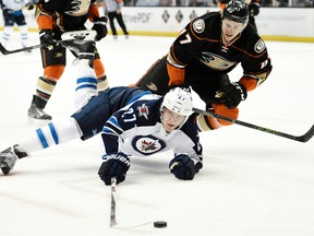 Winnipeg Jets right wing Nikolaj Ehlers, front, of Denmark, lunges for the puck as he falls to the ice while under pressure by Anaheim Ducks defenseman Hampus Lindholm, top, of Sweden, during the first period of an NHL hockey game in Anaheim, Calif., Tuesday, April 5, 2016. (AP Photo/Kelvin Kuo)