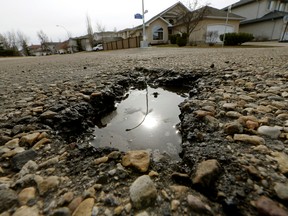 The sun is reflected in a water-filled pothole on a residential road in southwest Edmonton on April 5, 2016. (PHOTO BY LARRY WONG/POSTMEDIA NETWORK)