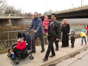 A group of Syrian refugees walk along the Thames River near the forks on Tuesday March 15, 2016. (Free Press file photo)
