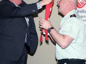 Mike Ryan, regional deputy commissioner of the Ontario region of Correctional Service Canada and the 2015 United Way campaign chair, hands over the traditional red suspenders to Col. Stephen Kelsey, commander of CFB Kingston and 2016 campaign chair, at the 2016 Workplace Volunteer Awards on Wednesday. (Steph Crosier/The Whig-Standard)