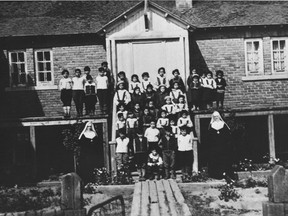 Native children and nuns are seen in front of a residential school in Maliotenam, Que., circa 1950. (Library Archives of Canada)