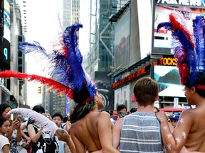 In this July 28, 2015, file photo, a tourist poses for a photo with two women clad in thongs and body paint in New York's Times Square. Topless women posing for photos in Times Square are causing headaches for politicians and law enforcement who wish to regulate their presence but have no clear idea how. (AP Photo/Julie Jacobson, File)