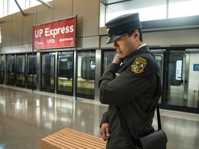 A uniformed employee listens to his radio on the platform at Pearson Airport with Toronto's UP Express in the background. Craig Robertson/Toronto Sun/Postmedia Network