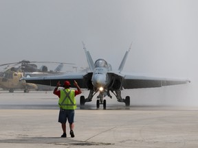 A CF-188 Hornet from the 425 Alouettes, Tactical Fighter Squadron, 3 Wing Bagotville, Quebec, is guided under a water salute during media day for the Canadian International Air Show at Pearson Airport in Toronto, Ontario, September 3, 2015.  REUTERS/Louis Nastro