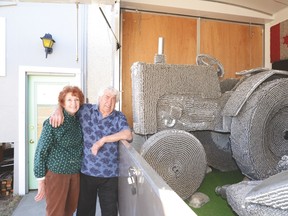 Victoria and Doug Fibke stand next to a tractor Doug constructed using pop tabs and other recycled materials. His sculptures include more than three million pop tabs. - Photo by Marcia Love