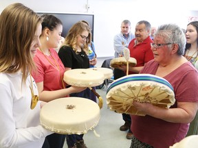 Dominique Labelle, left, Desiree Demers, and Maxine Lemieux participate in a birthing ceremony of traditional Native drums with Native elders Julie and Frank Ozawagosh, of Atikameksheng Anishnawbek, at Ecole secondaire du Sacre-Coeur in Sudbury, Ont. on Friday April 8, 2016. John Lappa/Sudbury Star/Postmedia Network
