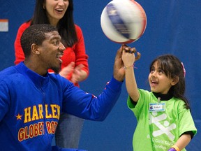 Harlem Globetrotter Anthony (Buckets) Blakes entertained Syrian refugee children Friday, including six-year-old Sadeel Allo, at the Boys and Girls Club. (DEREK RUTTAN, The London Free Press)