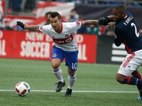 Toronto FC's Sebastian Giovinco holds off a New England Revolution defender during Saturday's game. (AP)