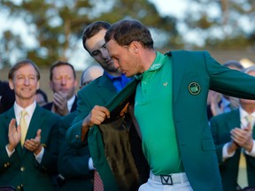 Defending champion Jordan Spieth, left, helps 2016 Masters champion Danny Willet, of England, put on his green jacket following the final round of the Masters golf tournament Sunday, April 10, 2016, in Augusta, Ga. (AP Photo/Jae C. Hong)