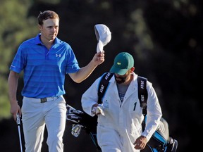 An unhappy Jordan Spieth tips his cap to the crowd as he walks up the 18th fairway at Augusta National yesterday. The defending champion had a five-stroke lead as he entered the back nine, but stumbled on holes No. 10, 11, and, especially, 12. (The Associated Press)