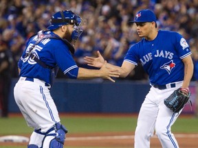 Blue Jays pitcher Roberto Osuna (right) and catcher Russell Martin celebrate after their team’s 3-0 win over the Boston Red Sox on April 10, 2016, at the Rogers Centre. Osuna has recorded three saves in the first week of the regular season and has an ERA of 0.00. (FRED THORNHILL/The Canadian Press)