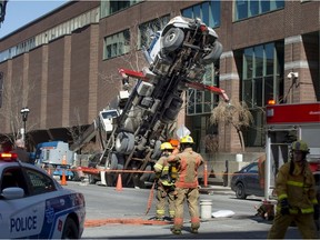 Firefighters work around a crane that toppled over on rue St. Denis in Montreal, on Sunday, April 10, 2016. (Peter McCabe/MONTREAL GAZETTE)