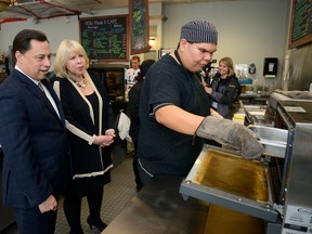Ontario Economic Development Minister Brad Duguid and London North Centre MPP Deb Matthews watch Quinton Doxtator works at the Youth Opportunities Unlimited Cafe in London, where they announced a new program Monday. (MORRIS LAMONT, The London Free Press)