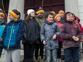 Grades 4 and 5 students from Sydenham Public School participate in raising a banner of peace on the tower of Chalmers United Church in Kingston. (Photo by Hannah Lawson/For The Whig-Standard)