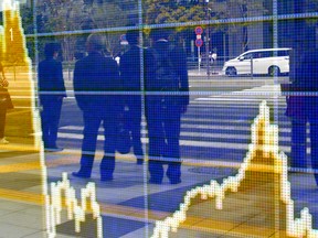 In this April 8, 2016 file photo, people are reflected on the electronic board of a securities firm in Tokyo. The IMF on Tuesday, April 12 downgraded its outlook for growth for most regions and for the global economy as a whole. It now foresees a weaker financial landscape than it did in January. Like the World Bank and the Organization for Economic Cooperation and Development, the IMF has repeatedly overestimated the strength of the world economy in the aftermath of the 2008 financial crisis. (AP Photo/Shizuo Kambayashi)