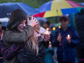 People gather outside the home of Ingrid Lyne during a candlelight vigil hosted by St. Matthew's Lutheran Church in Renton, Wash., Tuesday, April 12, 2016. The church hosted the vigil on behalf of Lyne after remains believed to be those of Lyne were found over the weekend in a homeowner's recycling bin. (Dean Rutz/The Seattle Times via AP)