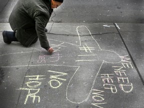 An Idle No More member makes a chalk drawing outside of Indian Northern Affairs Canada offices in solidarity with Attawapiskat on Wednesday, April 13, 2016, in Toronto. (Veronica Henri/Toronto Sun)