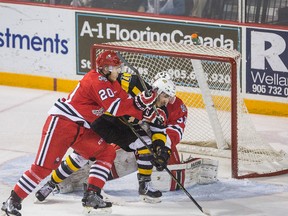 The Kingston Frontenacs’ Jared Steege reaches for the puck while he is sandwiched between Niagara IceDogs Josh Wesley and goalie Alex Nedeljkovic during Ontario Hockey League playoff action in St. Catharines on Wednesday night. (Bob Tymczyszyn/Postmedia Network)