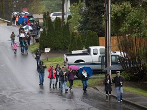 People walk towards the home of Ingrid Lyne for a candlelight vigil hosted by St. Matthew's Lutheran Church in Renton, Wash., Tuesday, April 12, 2016. The church hosted a vigil on behalf of Lyne after remains believed to be those of Lyne were found over the weekend in a homeowner's recycling bin. (Dean Rutz/The Seattle Times via AP)