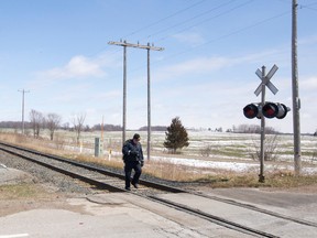 An OPP investigator takes photos after a VIA Rail passenger train collided with a car, killing its two occupants, at a level crossing with cross bucks and lights on Melbourne Drive north of Melbourne, Ont. on Monday April 4, 2016. (CRAIG GLOVER, Free Press file photo)