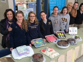 Members of the Social Justice Club and staff advisors with cakes for the school fundraising raffle.