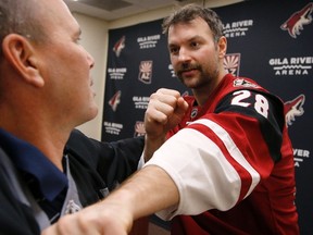 In this photo taken on Tuesday, Nov. 24, 2015, Arizona Coyotes' John Scott, right, gives Associated Press sports writer John Marshall, left, a hockey fighting tutorial, in Glendale, Ariz. The Coyotes traded Scott in January, 2016. (AP Photo/Ross D. Franklin)