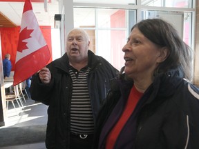 Don Grimshaw proudly holds up a Canadian flag while he and Joan Brennan sing O Canada at McDonald's in Port Hope, Ont. (Pete Fisher/Northumberland Today/Postmedia Network)