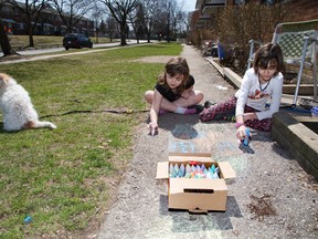Emma Thomas, 9, (left) and friend Anniek Pitt, 10, are breaking the rules by drawing with chalk in front of Pitt's home. Derek Ruttan/The London Free Press