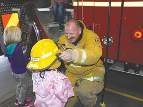 Firefighter Ron Cooper lets Aurora Regular, 5, try on his helmet during a Ronald McDonald House field trip to the Spruce Grove Fire Hall on April 8. Photo by Marcia Love