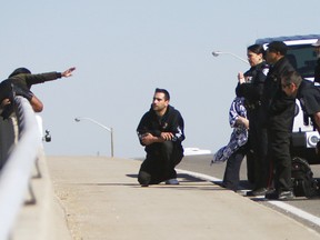 Police officers from Toronto Police, Durham Region, and the OPP work together to help a woman who had climbed over the railing on the Meadowvale Road bridge over the eastbound lanes of Highway 401 in Toronto at around 10:00 am on Friday, April 15th, 2016. Officers were able to help her back over the railing to safety. Kevin Lamb/Toronto Sun/Postmedia Network