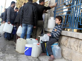 A boy waits to fill water containers while residents wait in line in Bab Neirab, Aleppo, Syria February 15, 2016. REUTERS/Abdalrhman Ismail