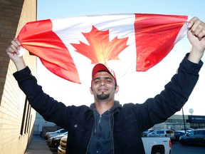 James Akam, an Afghan who risked his life as an interpreter for the Canadian Forces during the war in his homeland, enjoys some time with a Canadian flag on Friday after arriving at Pearson airport to start a life in Canada. (Michael Peake/Toronto Sun/Postmedia Network)