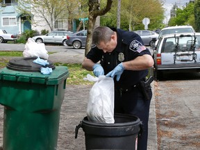 Seattle Police officer Aaron Stoltz searches garbage and recycling bins, Friday, April 15, 2016, after human remains were found in a nearby container in Seattle. Seattle Assistant Police Chief Robert Merner said authorities were investigating the probable connection between the remains found Friday and the recent murder of Ingrid Lyne, whose partial remains were found in a recycling bin earlier in the week. (AP Photo/Ted S. Warren)