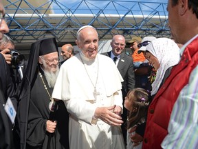 Pope Francis, flanked by Ecumenical Patriarch Bartholomew I, spiritual leader of the world’s Orthodox Christians, greet a group of refugees at the airport of Mytilene on the Greek island of Lesbos, Saturday, April 16, 2016. Pope Francis gave Europe a provocative and concrete lesson in how to treat refugees Saturday by bringing home 12 Syrian Muslims aboard his charter plane after an emotional visit to the hard-hit Greek island of Lesbos. (Filippo Monteforte/Pool Photo via AP)