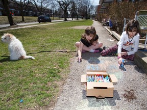 The landlords of Emma Thomas' (9) (left) and Anniek  (cct) Pitt's (10)townhouse complex have issued an edict banning sidewalk chalk Photo shot in London, Ont. on Friday April 15, 2016. Also pictured in Pitt's dog named Ruff-Ruff. Derek Ruttan/The London Free Press/Postmedia Network