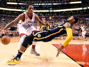 Raptors' DeMar DeRozan (left) picks up an offensive foul against Pacers' Paul George (right) during second half NBA playoff action in Toronto on Saturday, April 16, 2016. (Frank Gunn/THE CANADIAN PRESS)