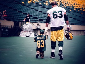 Edmonton Eskimos offensive lineman Brian Ramsay (63) walking on the sideline with his son after practice at Commonwealth stadium in Edmonton, AB. Wednesday, August 26, 2015