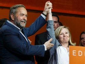 Federal NDP leader Thomas Mulcair lifts up new president Marit Stiles' hand after giving a concession speech after the party voted for a leadership review during the Edmonton 2016 NDP national convention at Shaw Conference Centre in Edmonton, Alta., on April 10, 2016. Ian Kucerak/Postmedia Network