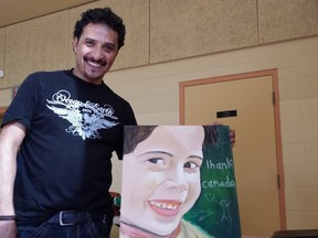 Mohamed Ali shows his painting representing a Syrian child crying tears of joy at a dinner for Syrian refugees like him served by Young Voices Can, made up of Jewish and Muslim high school students, at the Carleton Heights Community Centre Sunday.