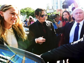 Johnny Depp, centre, and wife Amber Heard, left, arrive at the Southport Magistrates Court on the Gold Coast, Australia, Monday, April 18, 2016. Heard pleaded guilty to providing a false immigration document amid allegations she smuggled the couple's dogs into Australia. (Dave Hunt/AAP Image via AP)