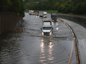 Trucks slowly drive through flood waters on North I-45 at North Main Street as White Oak Bayou comes over it's banks, flooding the freeway, Monday, April 18, 2016, in Houston. (Karen Warren/Houston Chronicle via AP)