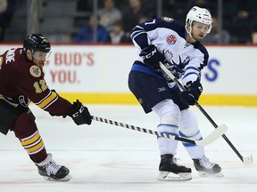 Manitoba Moose defenceman Josh Morrissey (right) shoots the puck while being bothered by Chicago Wolves centre Pat Cannone during AHL action in Winnipeg on Thu., Nov. 12, 2015. Kevin King/Winnipeg Sun/Postmedia Network
